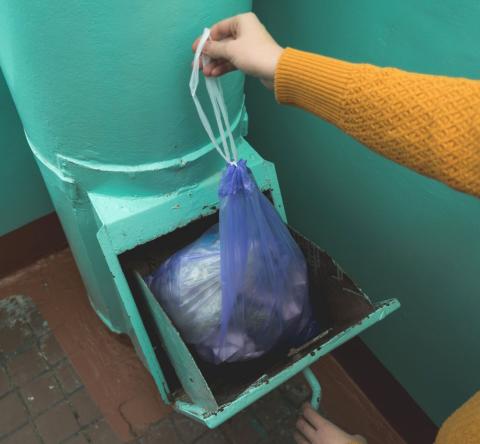 Personne jetant un sac poubelle par la trappe du vide-ordures