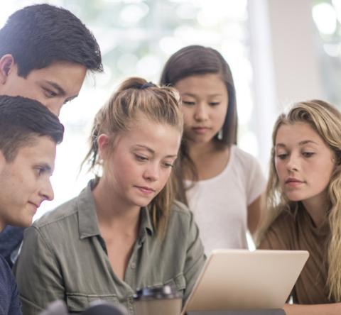 Un groupe de 5 étudiants étudie avec attention un contrat sur une tablette