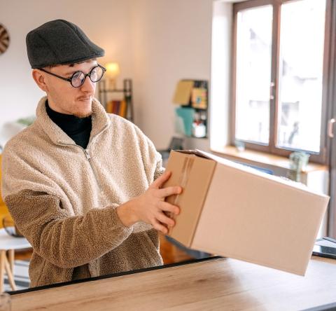 Un homme examine un colis sur le plan de travail de sa cuisine