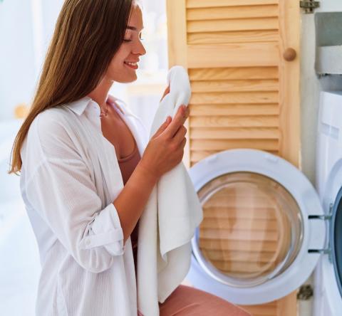 Une femme sort du linge propre de son lave-linge