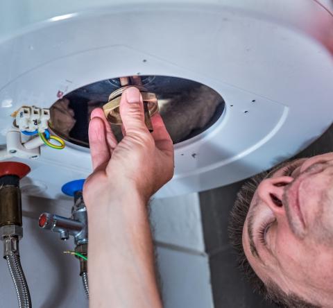 Un artisan réalise une intervention sur un ballon d'eau chaude
