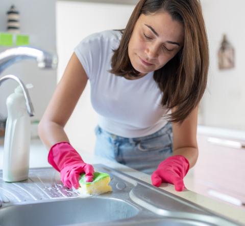 Une femme nettoie son évier en inox avec soin à l'aide d'une éponge